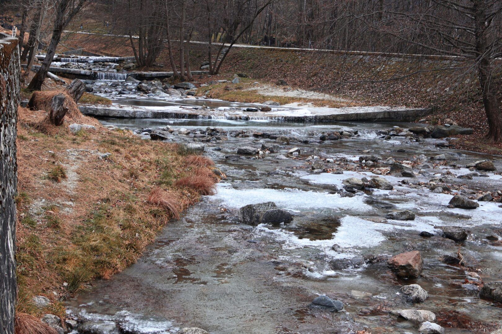 Peaceful winter scene of a partially frozen stream in Chiavenna,